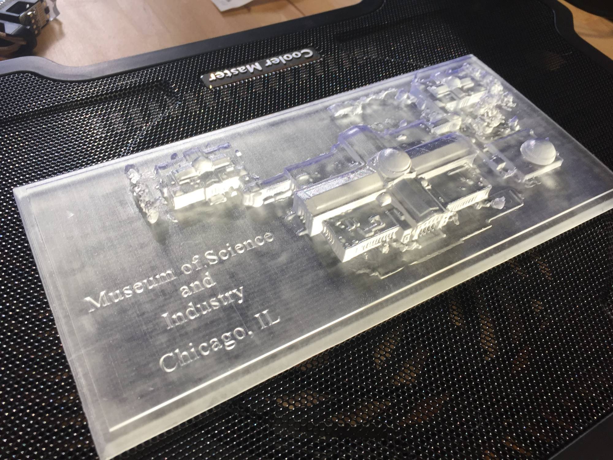 A small clear-resin 3D print of the museum on a rectangular base engraved with the words Museum of Science and Industry, Chicago, IL.