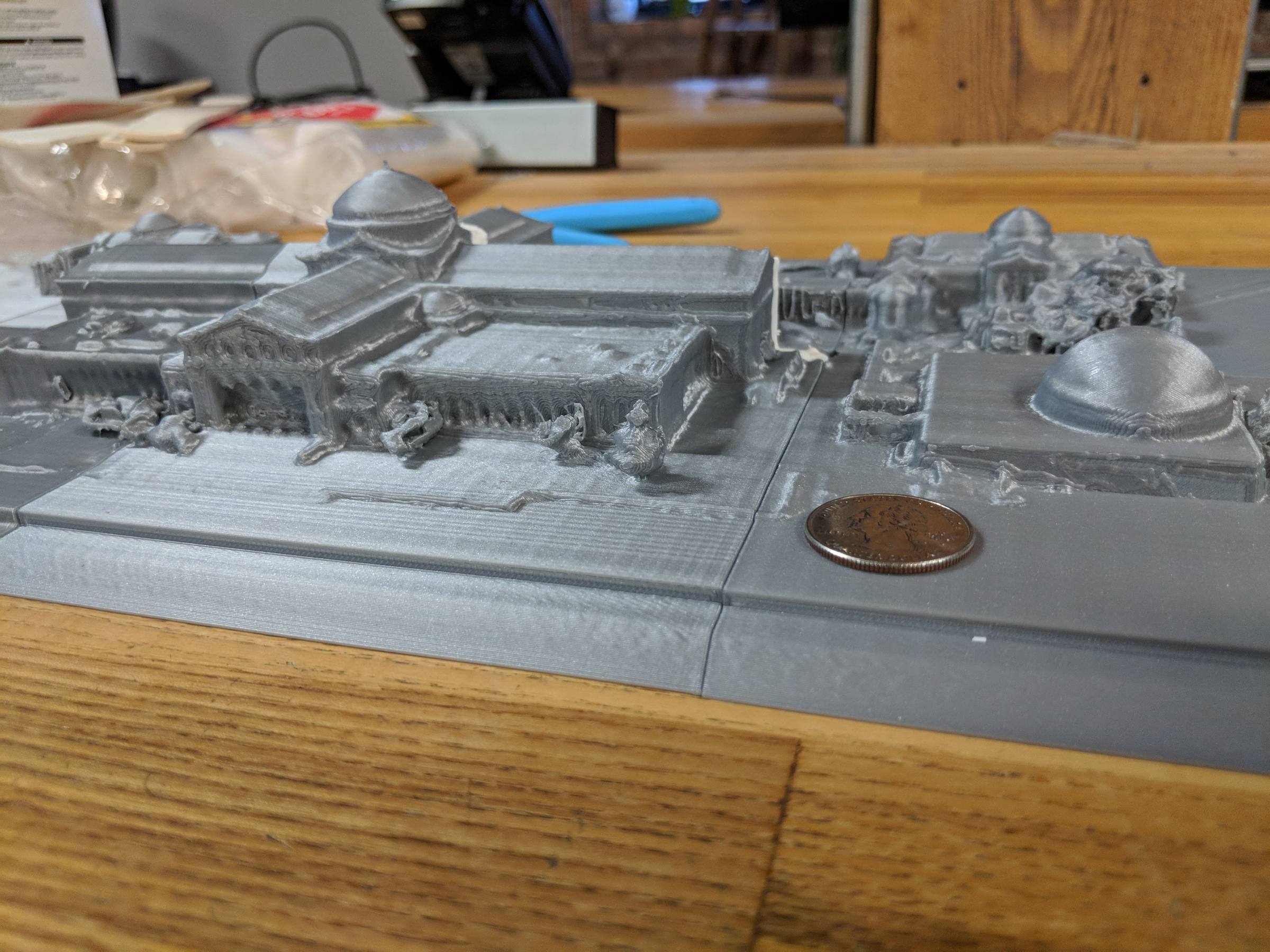 Close-up of grey 3D-printed sections of the museum, showing domes and colonnades, with a copper coin beside them for scale.