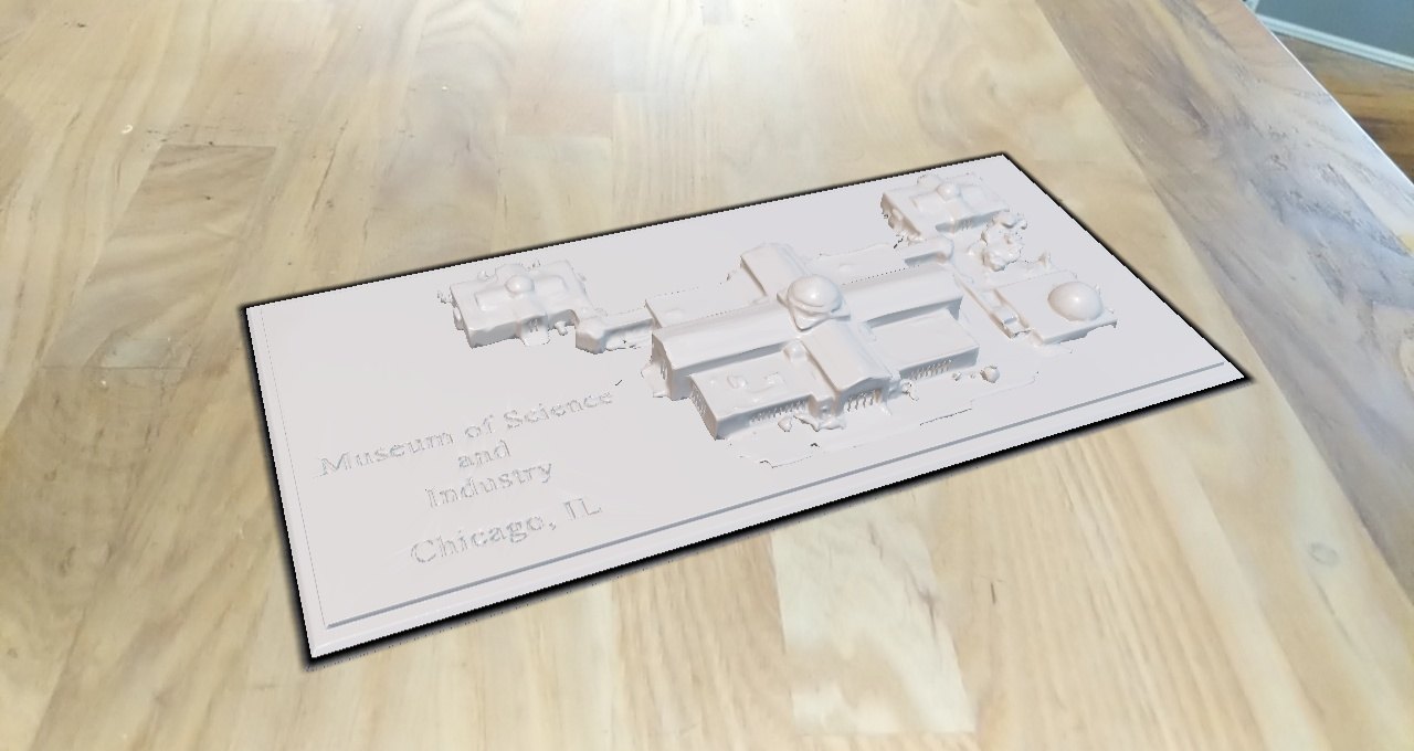 Phone screenshot of an augmented-reality white model of the museum appearing to sit on a wooden table.
